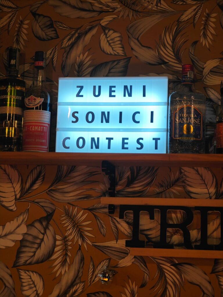 Insegna luminosa Zueni Sonici Contest tra le bottiglie del bancone